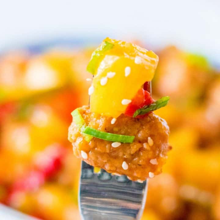 Sweet and sour meatball with pineapple and a red pepper on a fork.