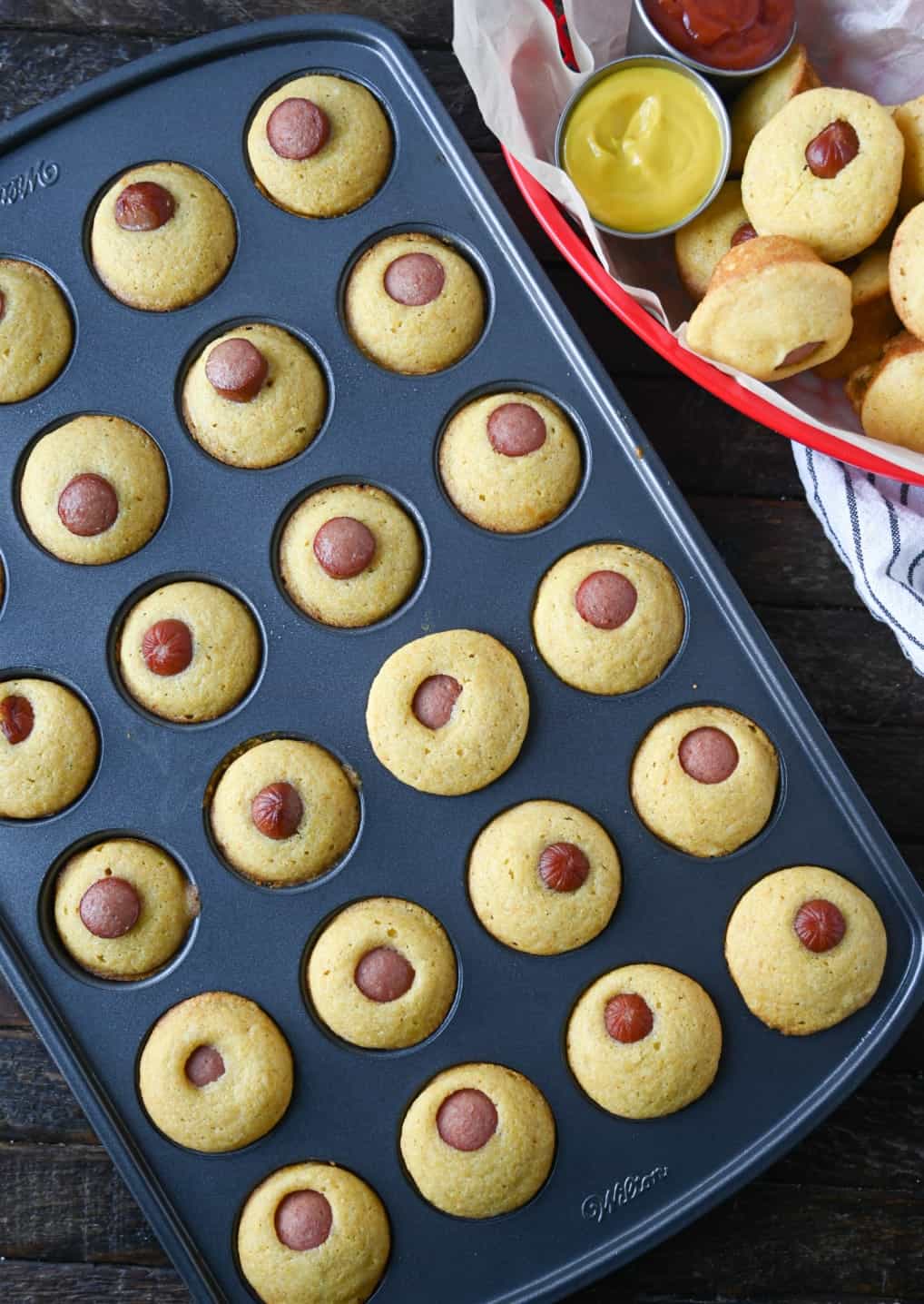 A muffin tin with 24 baked corn bread muffins.