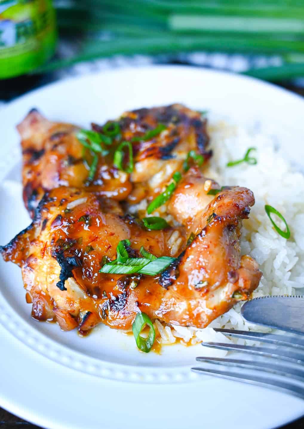 Peach chipotle chicken placed on top of coconut rice on a white plate.