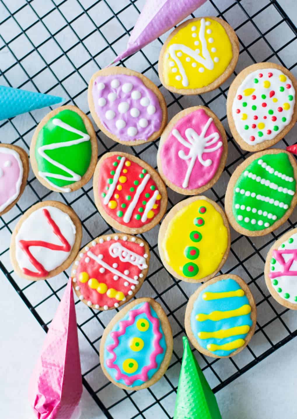 Easter egg cookies that have been decorated and laying on a cooling rack