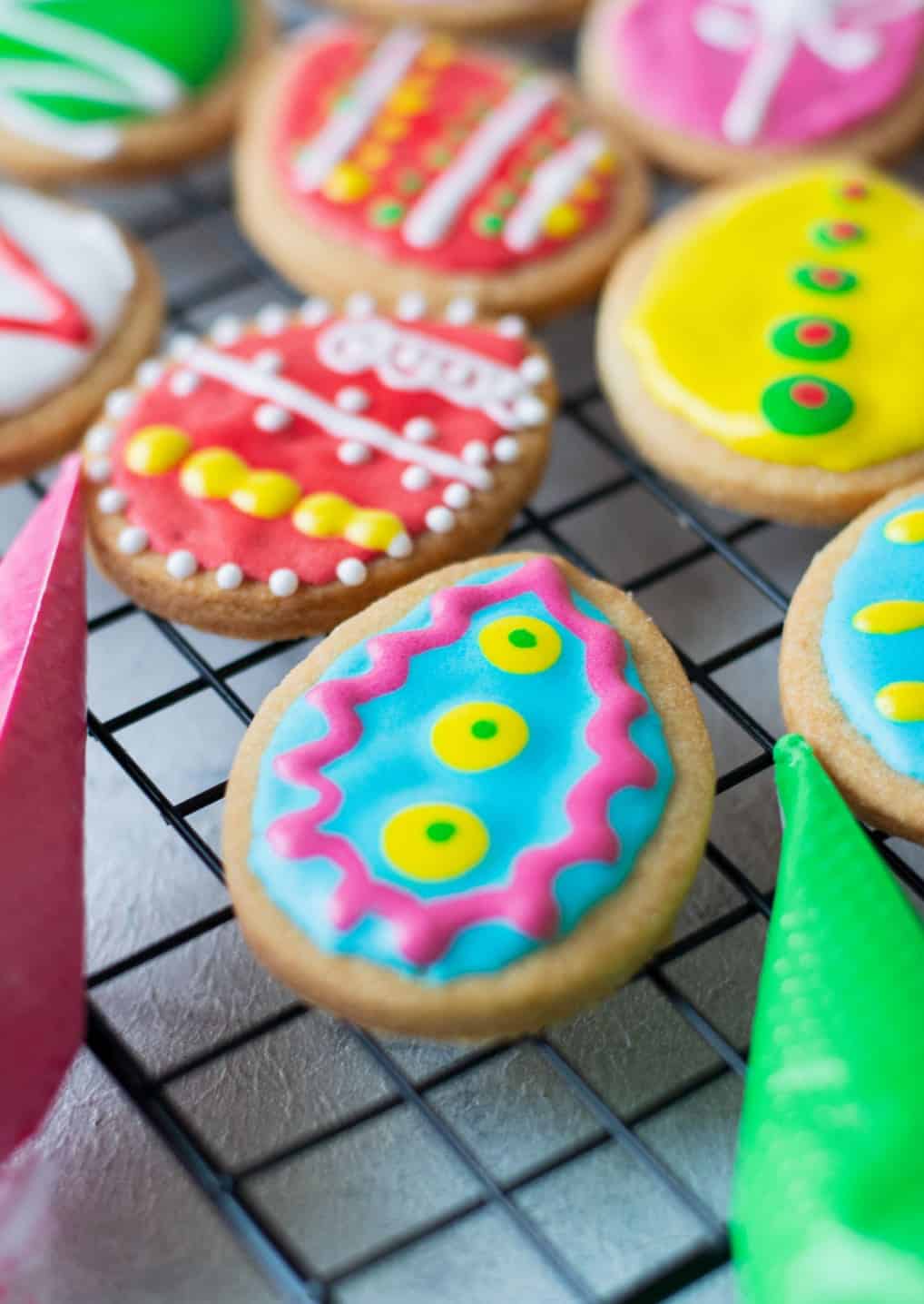 Close up photo of a decorated Easter egg cookie laying on a cooling rack.