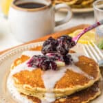 A stack of poppyseed pancakes with blueberry compote on top.