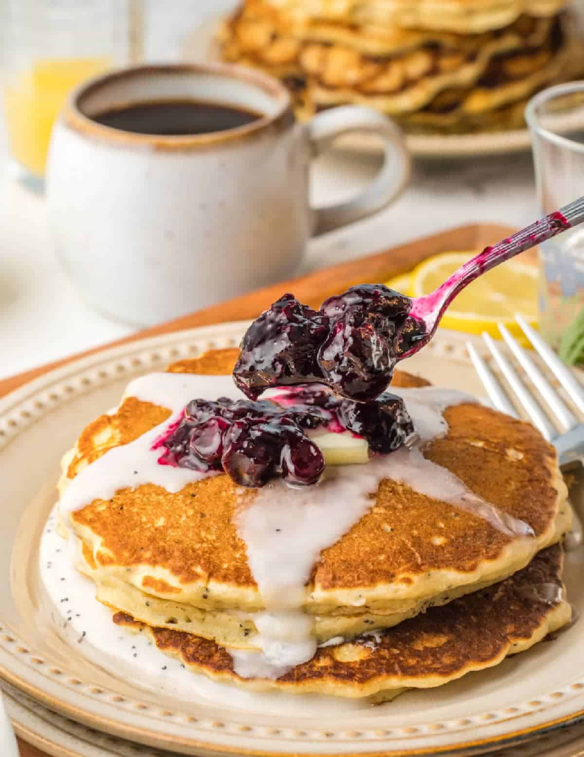A stack of poppyseed pancakes with blueberry compote on top.