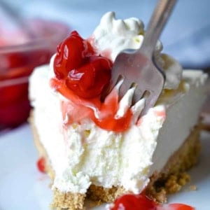 A close up photo of a fork cutting into a piece of cheesecake.