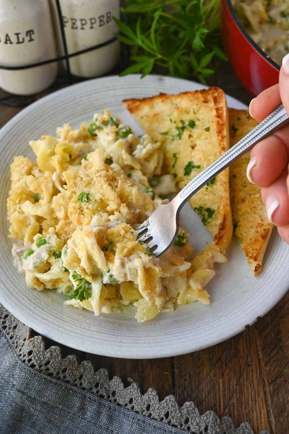 Tuna casserole on a plate with a fork taking a bite.