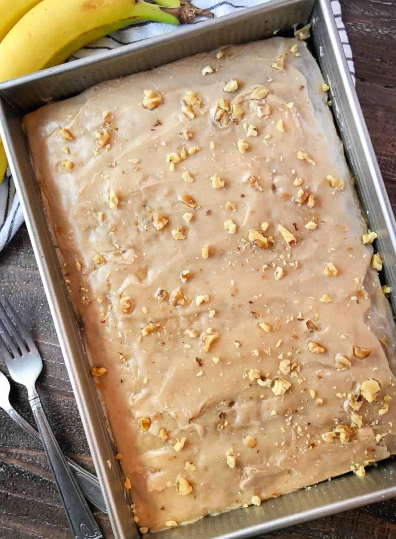 Cake baked in a pan and frosted with chopped walnuts on top.