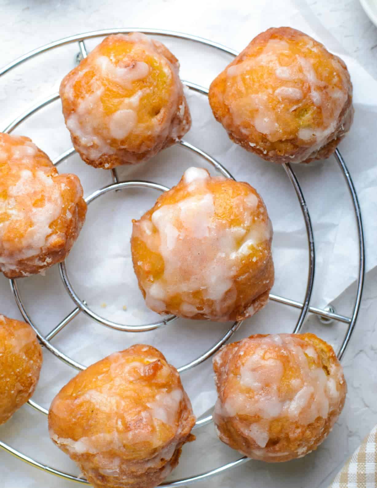 several banana fritters that have been dipped in glaze on a cooling rack.