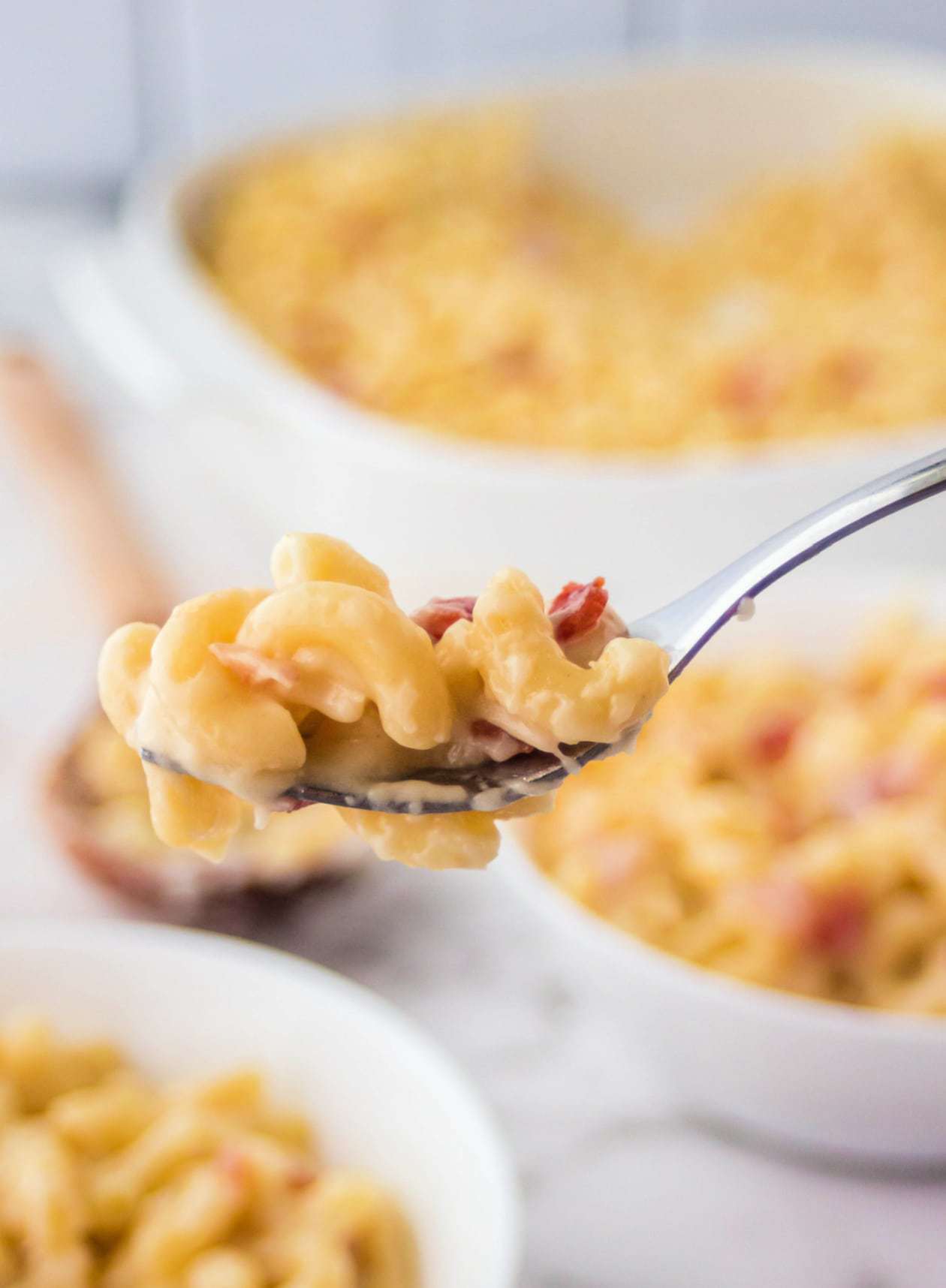 A spoon full of mac n cheese and bacon pieces.