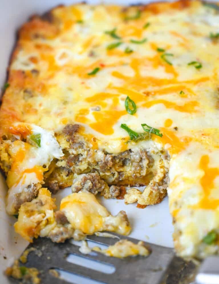 ABreakfast casserole in a white baking dish with a couple servings missing.