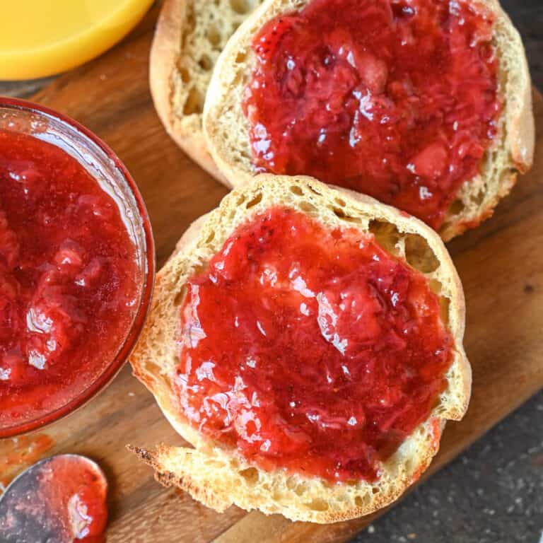 Strawberry jam spread onto english muffin.