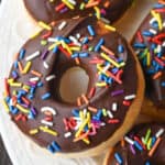 Donuts with chocolate frosting on a white platter.