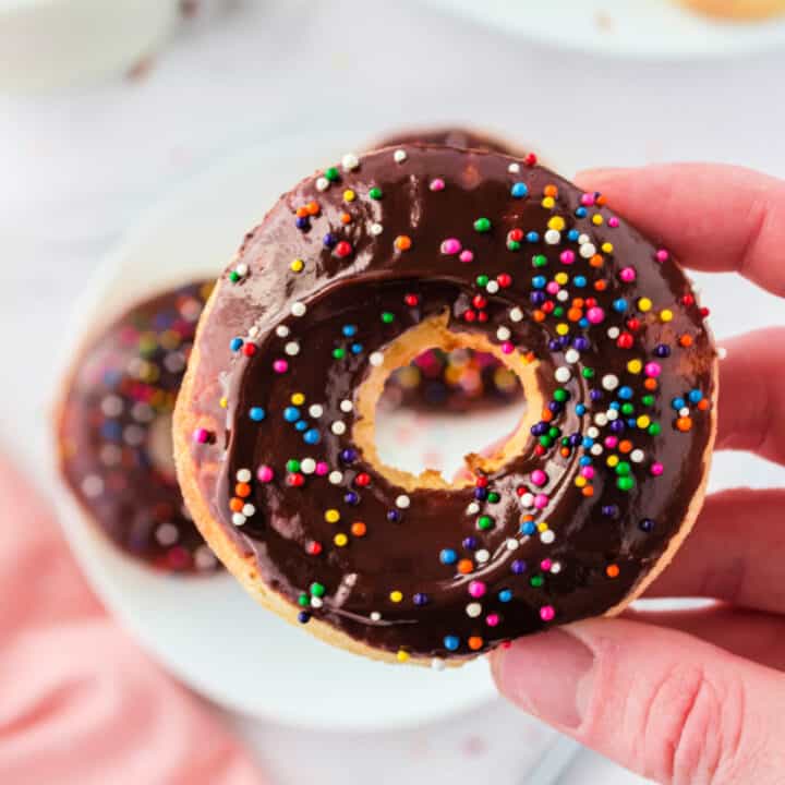 A chocolate dipped donut being held in a hand.