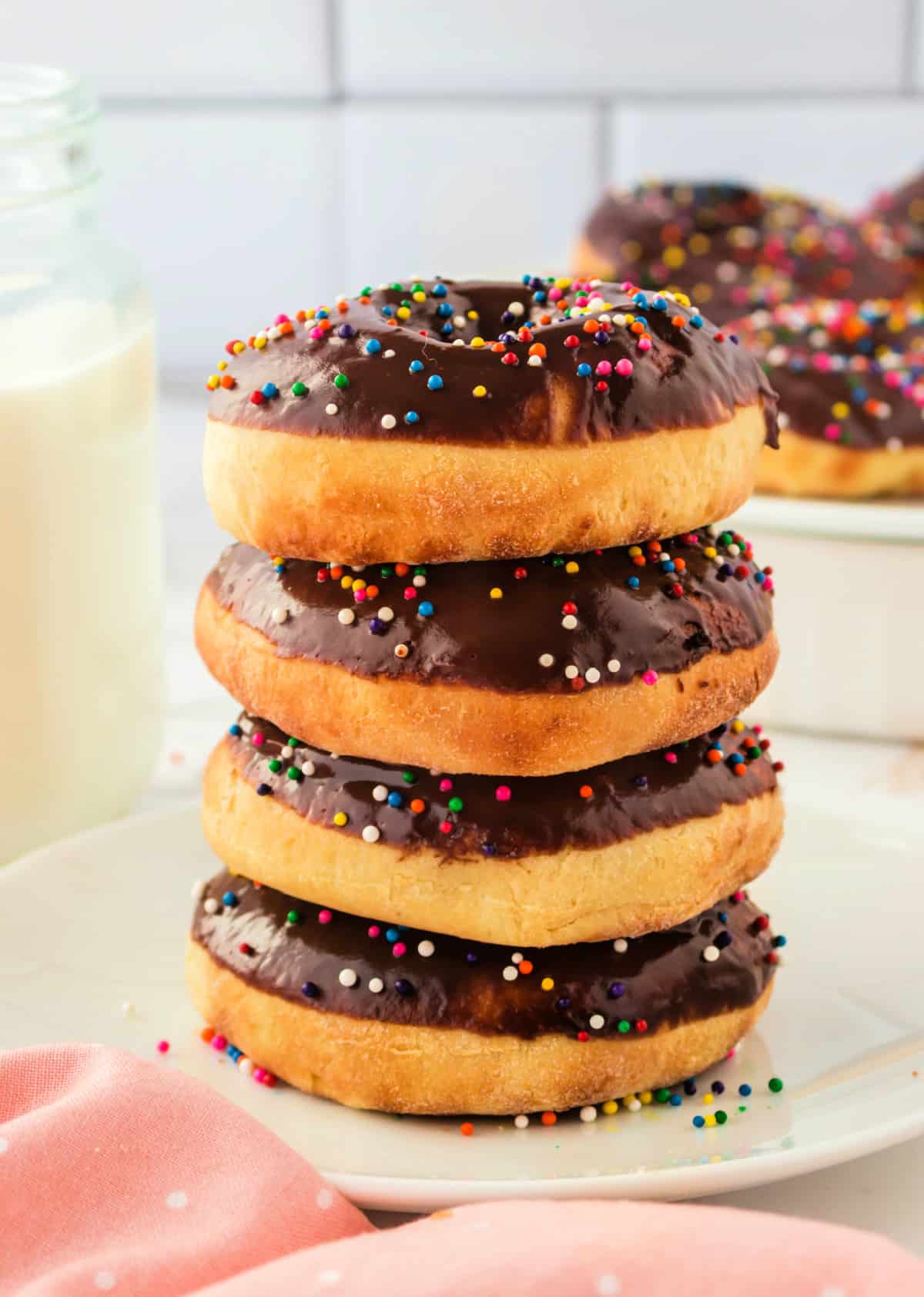 A stack of 4 air fried donuts with chocolate frosting and colorful sprinkles.