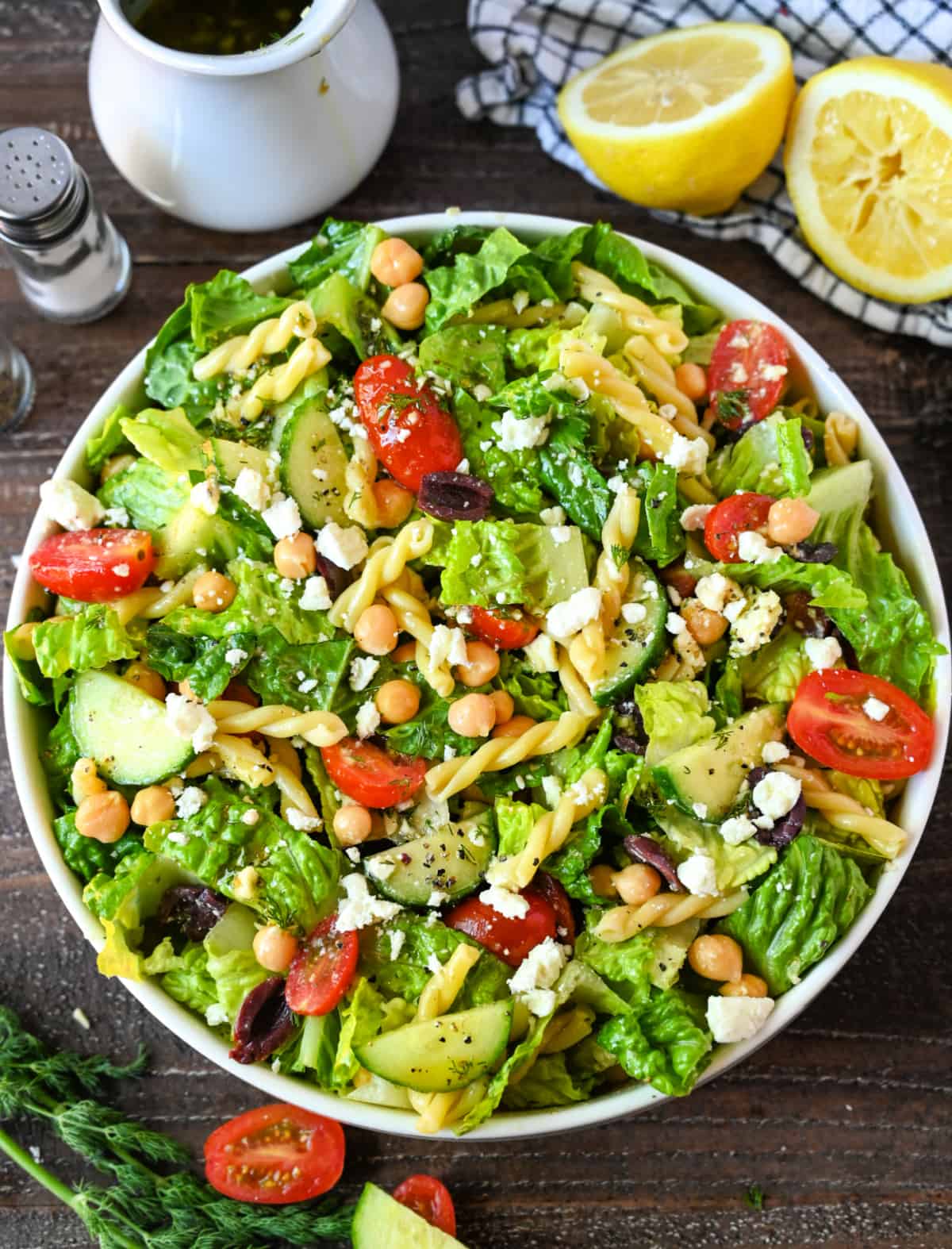 Chopped greek salad with vinaigrette all tossed together in a large white bowl.