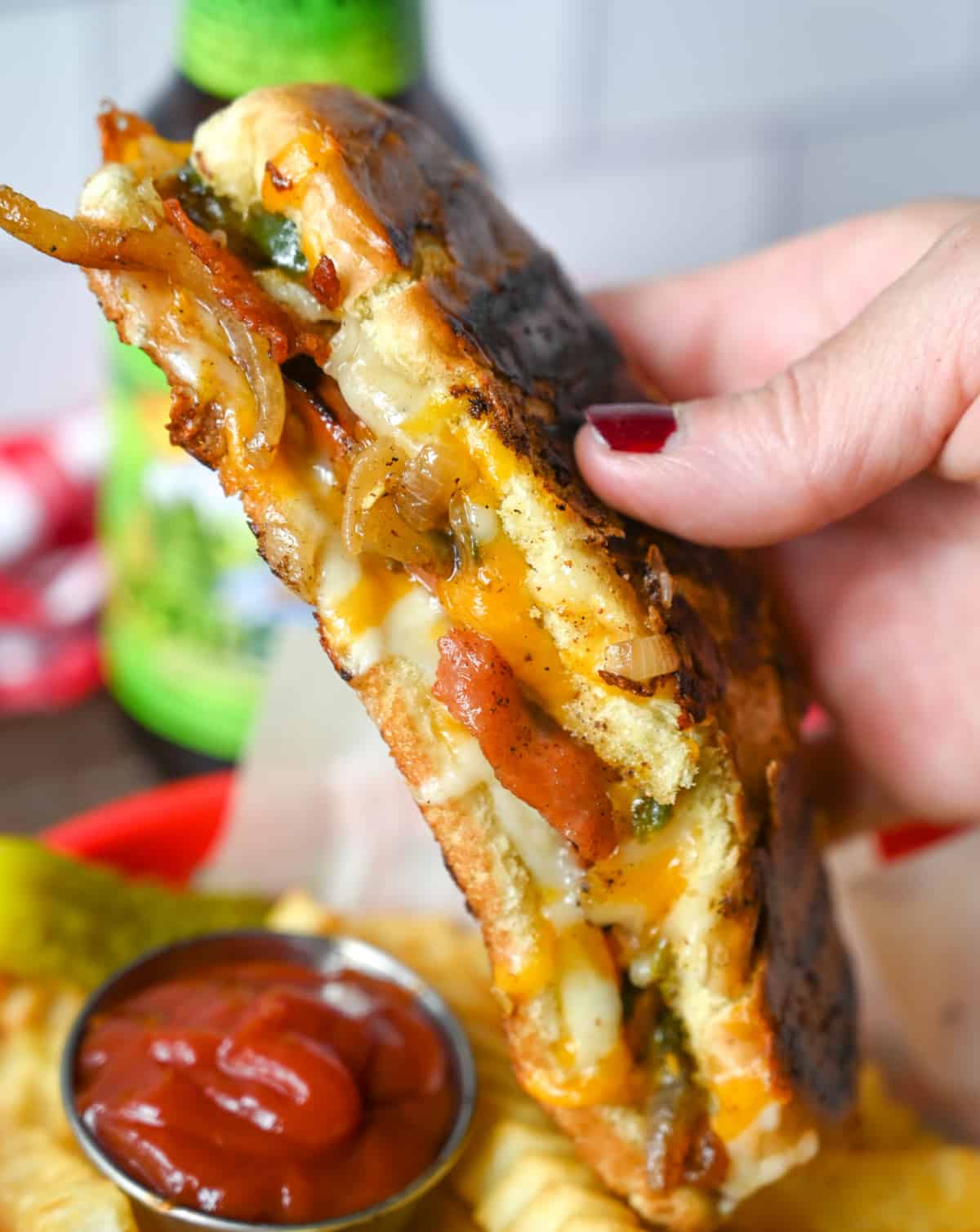 Hot dog grilled cheese is being held in a hand.