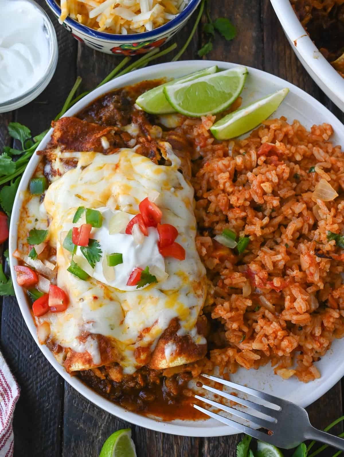 Ground beef enchilada on a plate with mexican rice.