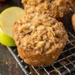 Apple muffin on a cooling rack with slices of apples.