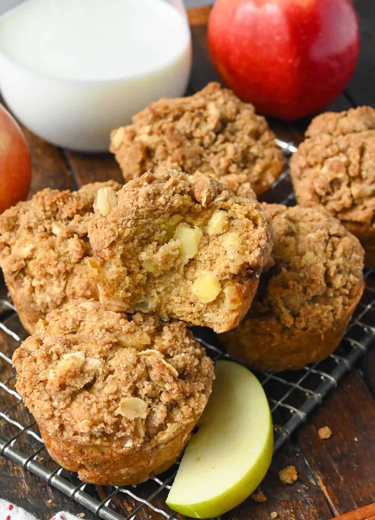 Apple spice muffins on a cooling rack and one with a bite out of it.