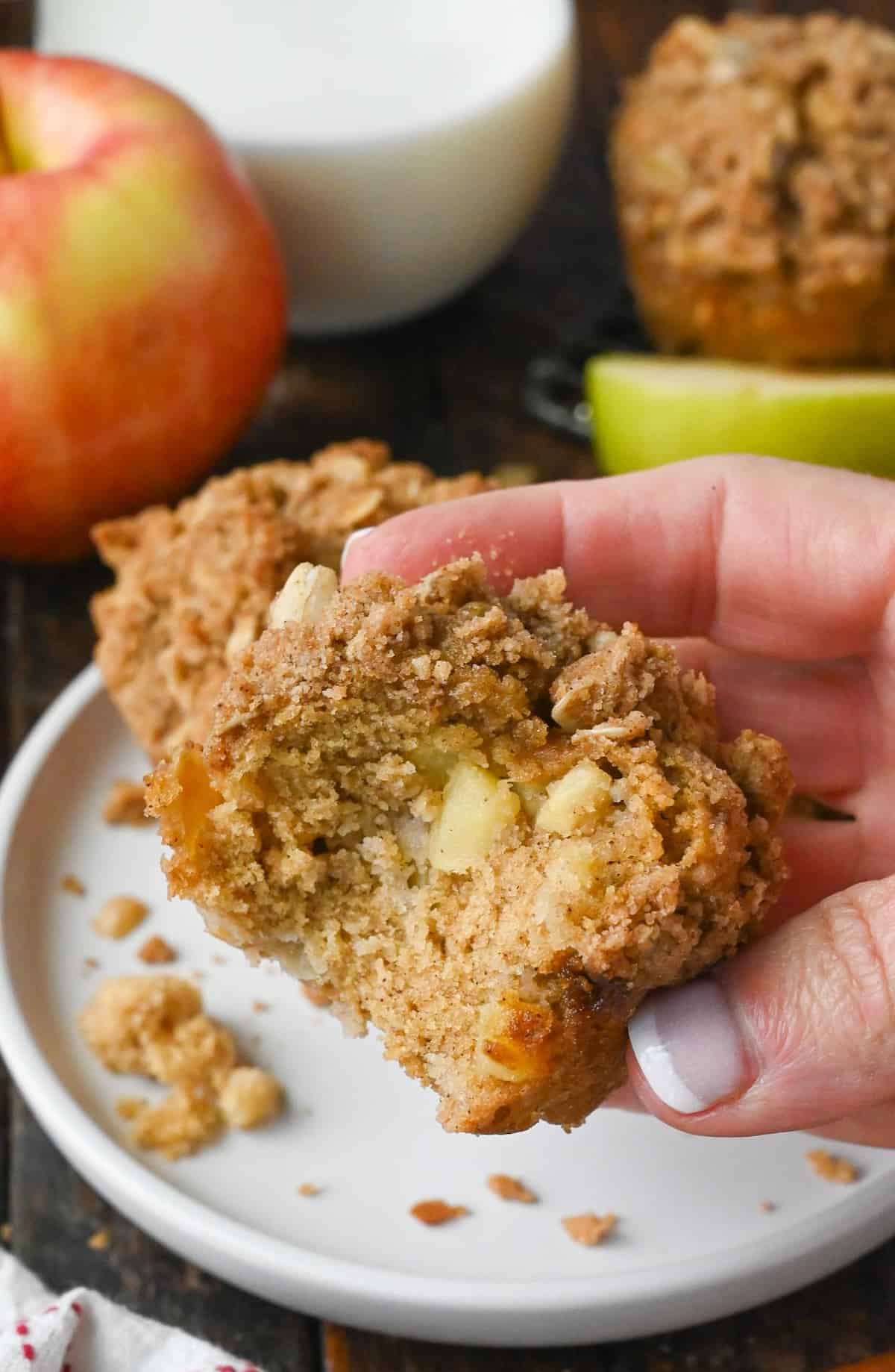 Apple spice muffin being held with a bite out of it.