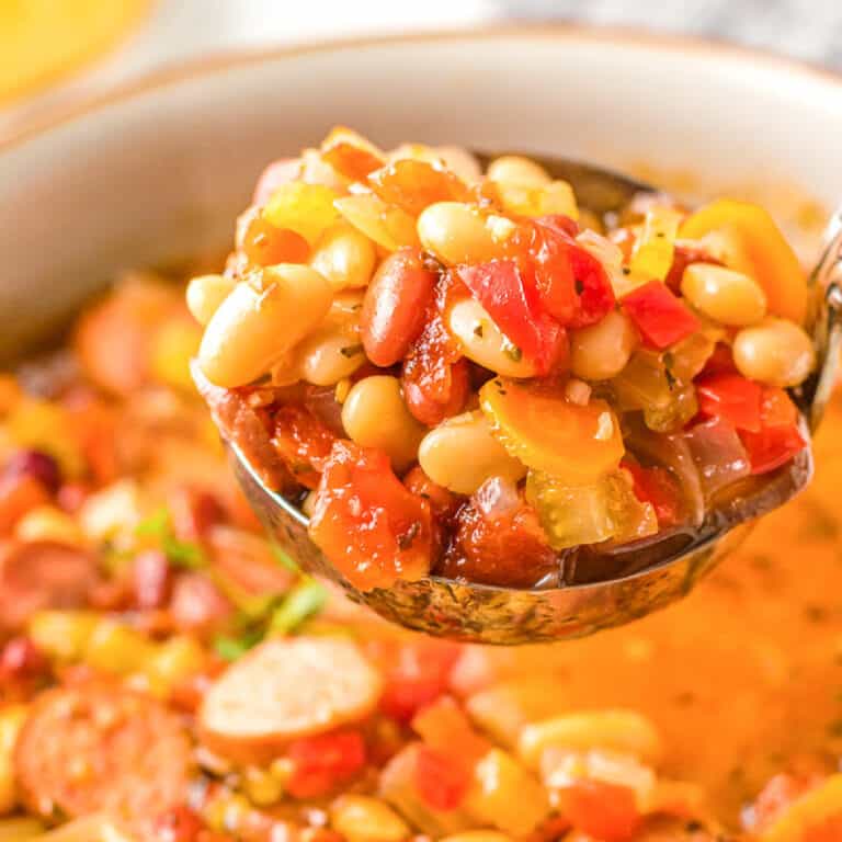 A close up photo of a ladle of sausage bean soup.