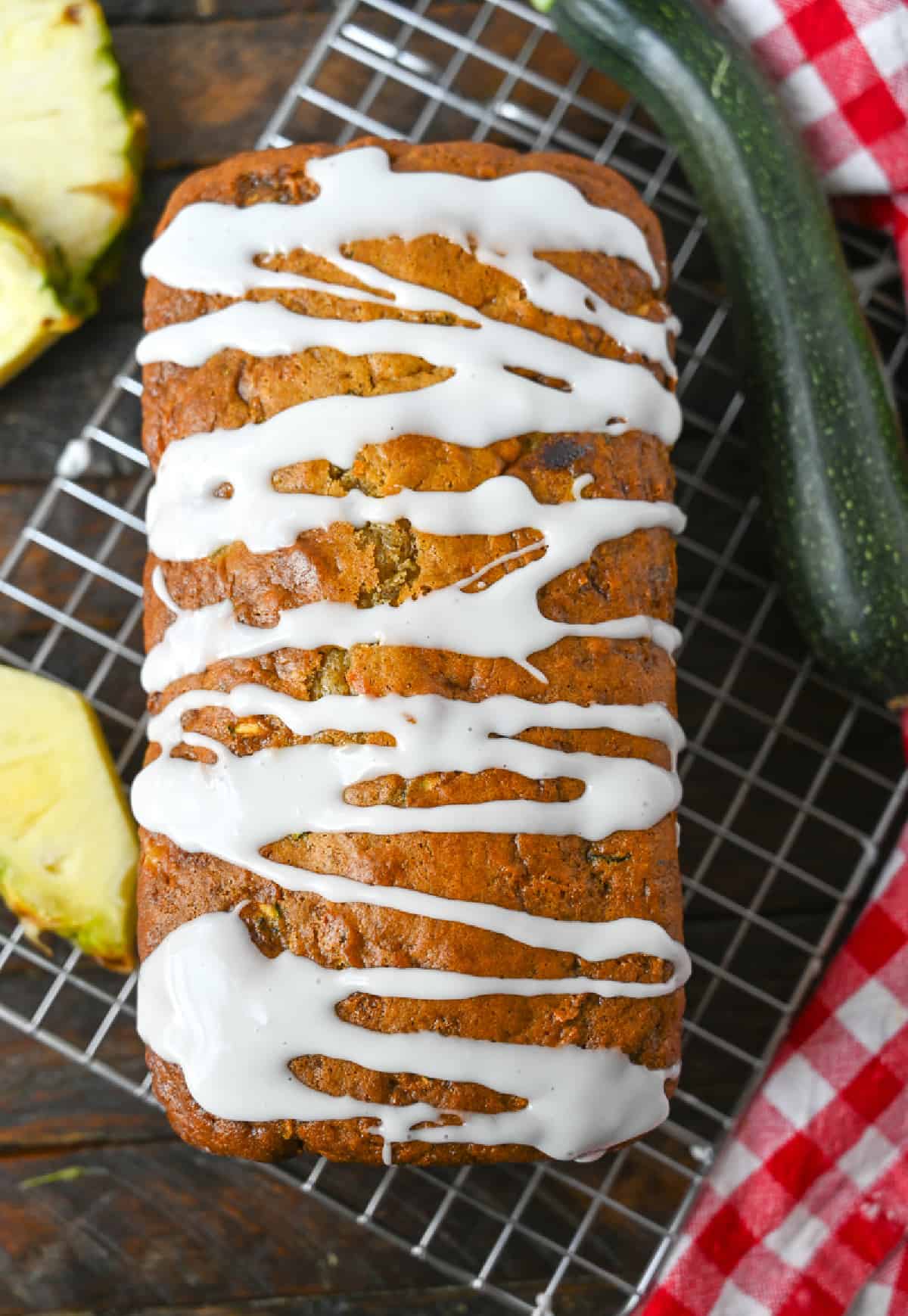 A loaf of pineapple zucchini bread with a glaze drizzled on top.