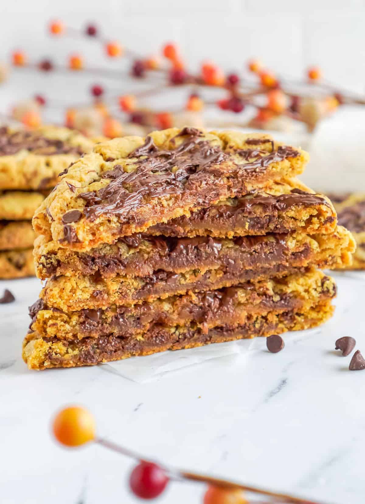 A stack of pumpkin chocolate chip cookies cut in half with melty chocolate.