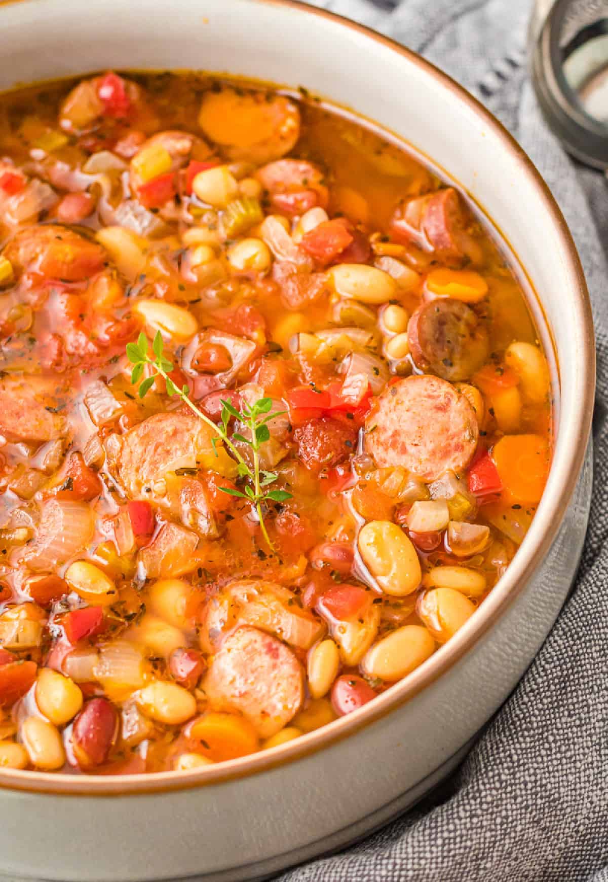 A close up photo of slow cooker sausage bean soup in a bowl.