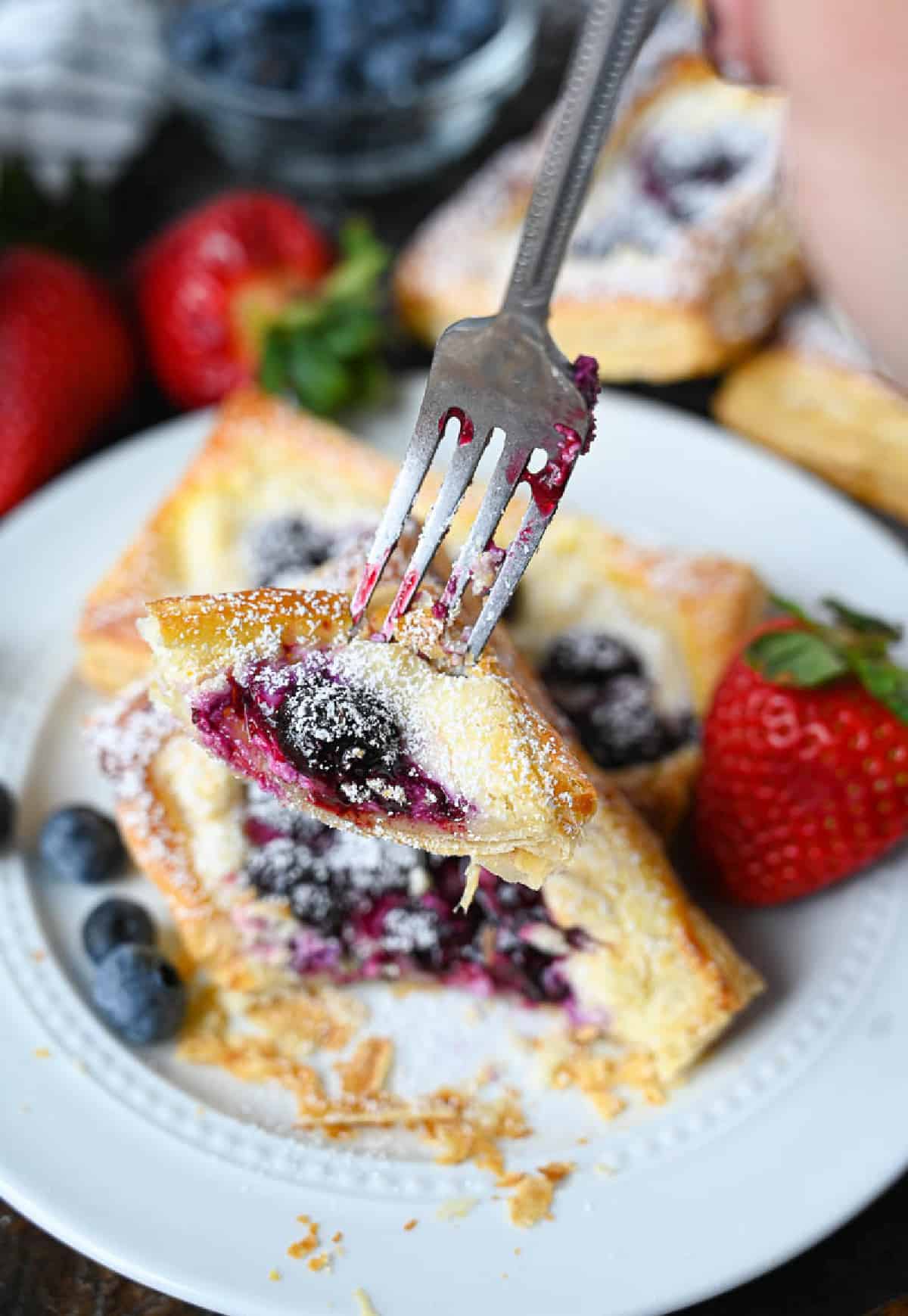 A fork picking up a bite of the danish.