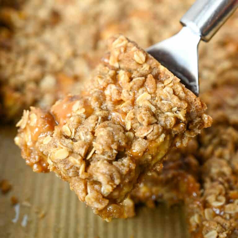 A metal spatula picking up a square of apple crumble.