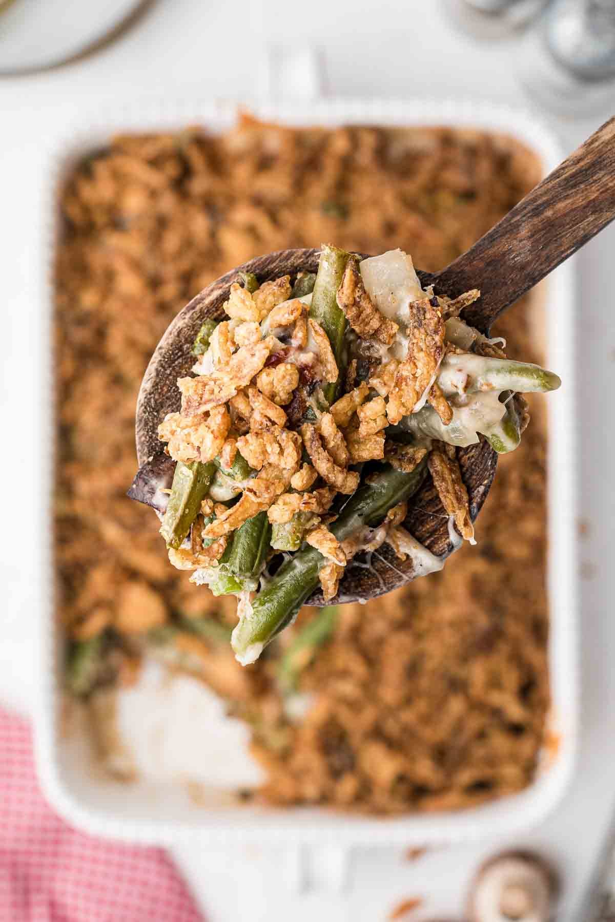 A wooden spoon picking up a scoop of green bean casserole.