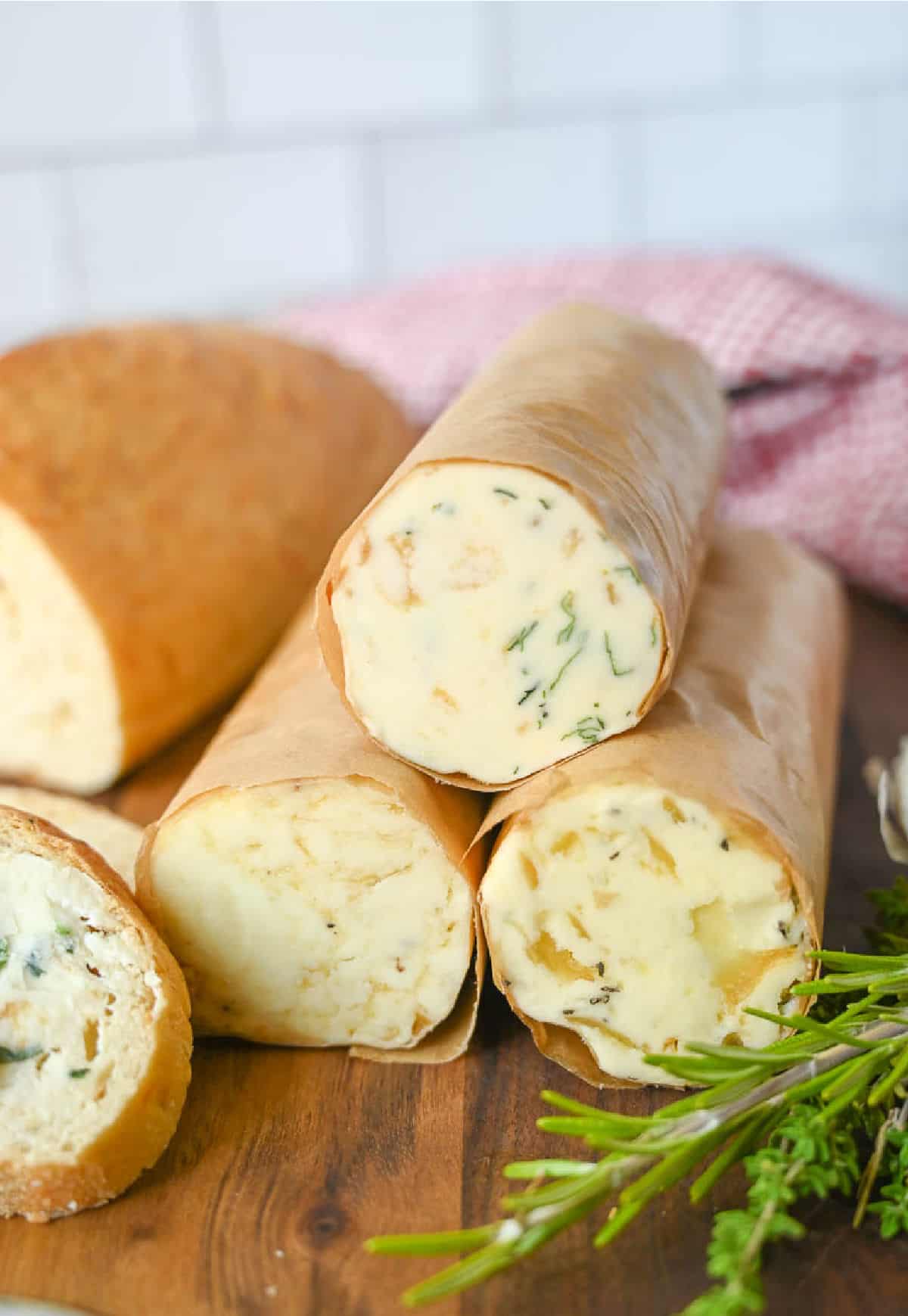 Three rolled herb compound butters in parchment paper.