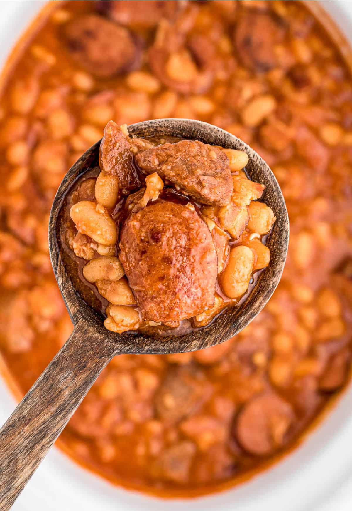 A wooden spoon scooping up dome white bean stew.