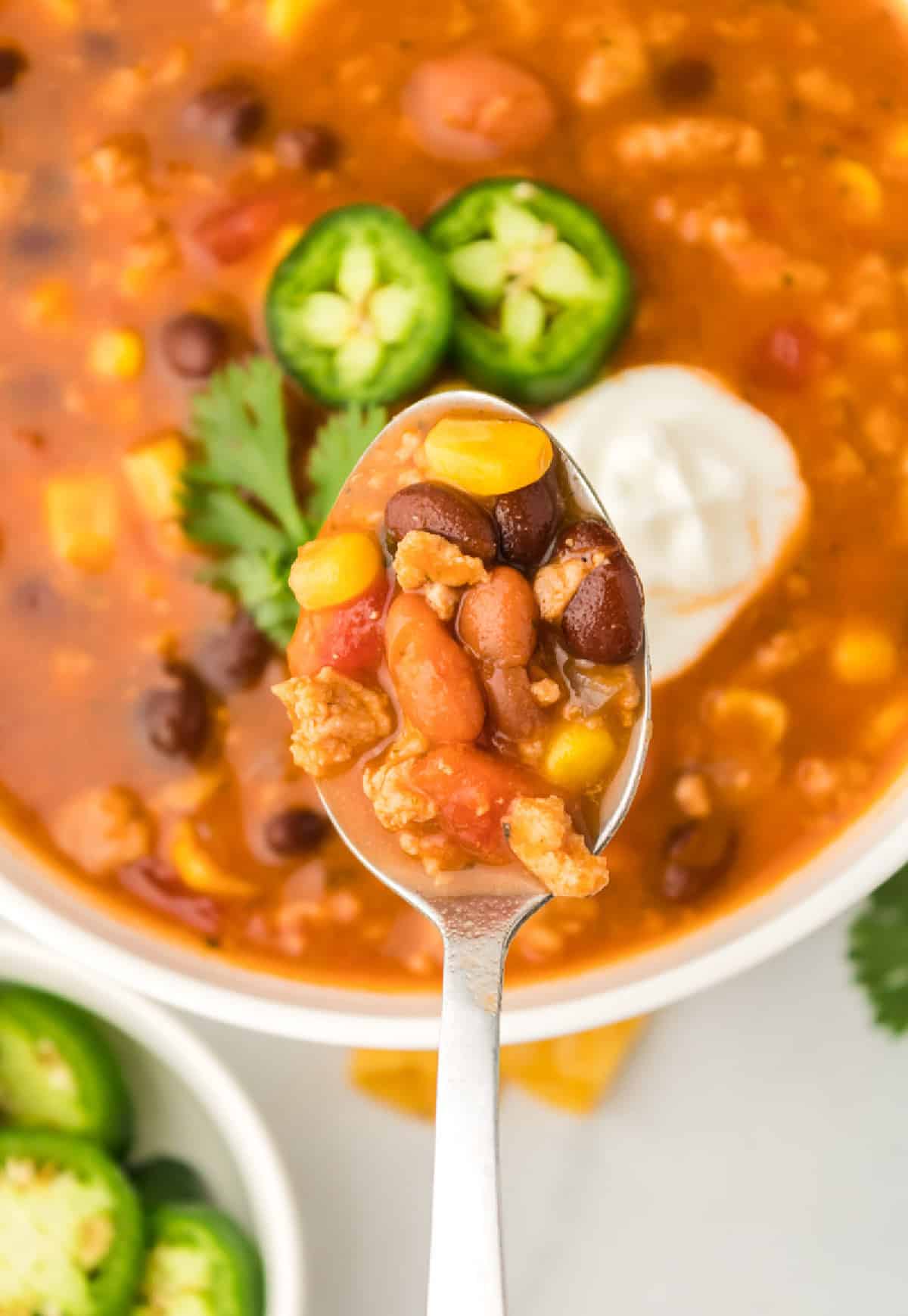 A spoon taking a bite out of a bowl of taco soup.