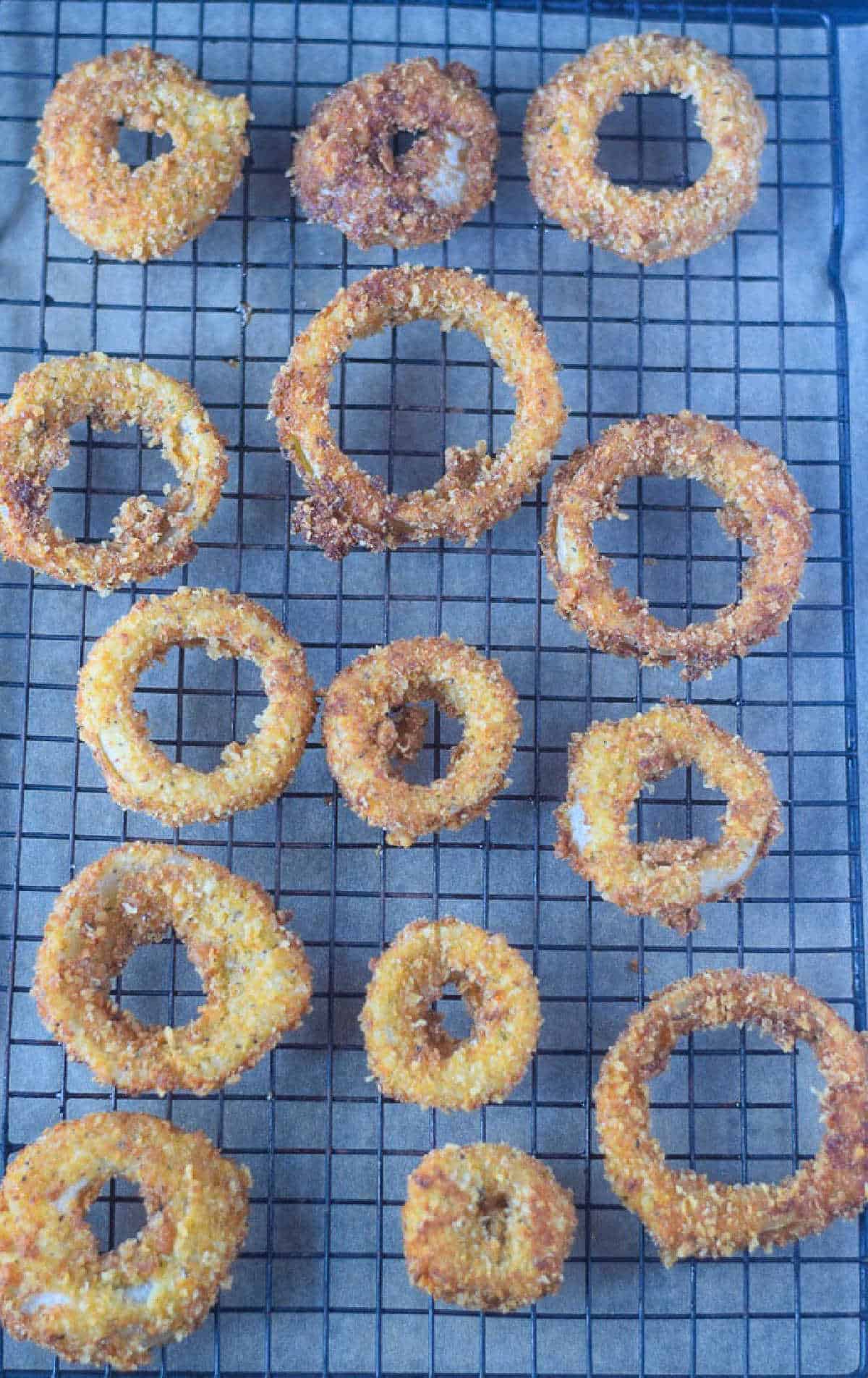 Parmesan onion rings fresh out of the oil and placed on a cooling rack.