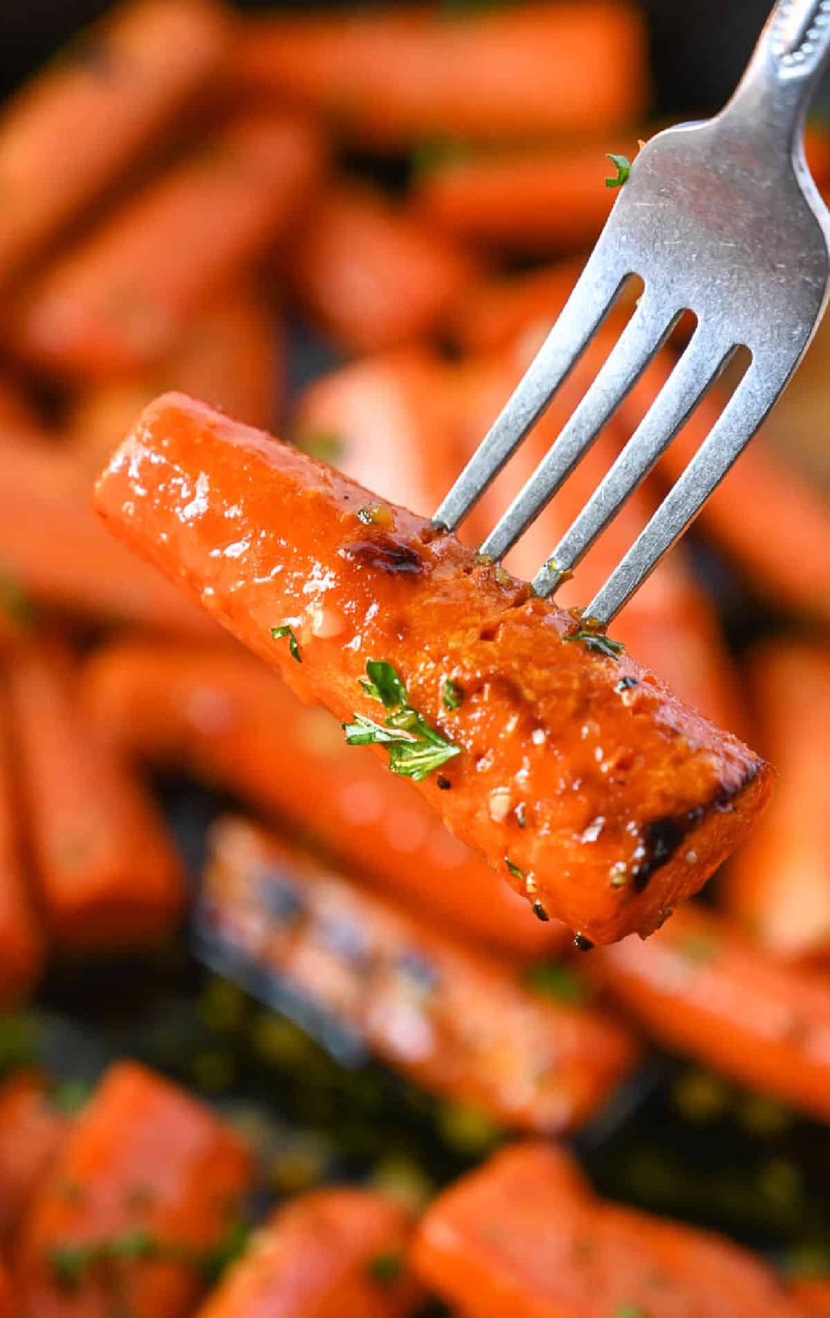 A fork picking up a roasted carrot.