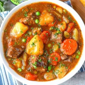 A close up photo of hearty beef stew in a white bowl.