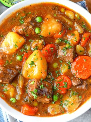 A close up photo of hearty beef stew in a white bowl.