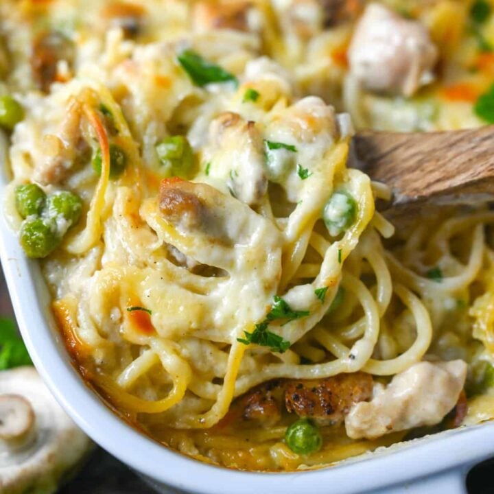 A close up photo of chicken tetrazzini being scooped up with a wooden spoon.