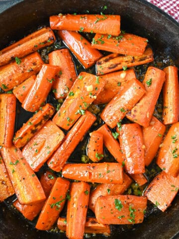 Carrots in a cast iron skillet tossed in honey garlic butter.