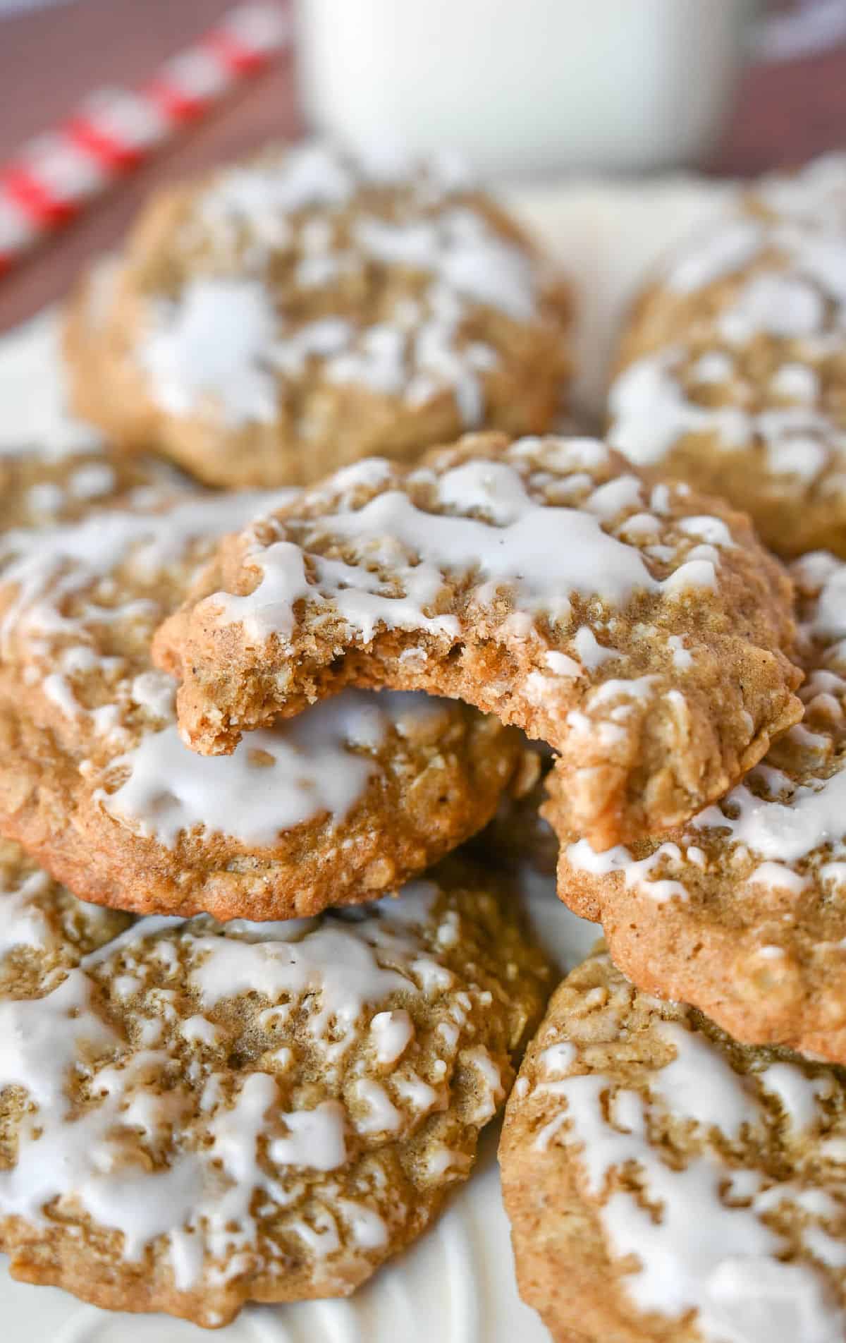 Iced oatmeal cookies on a plate and one with a bite out.