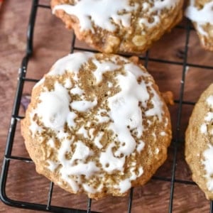 A close up photo of an iced oatmeal cookie on a cooling rack.