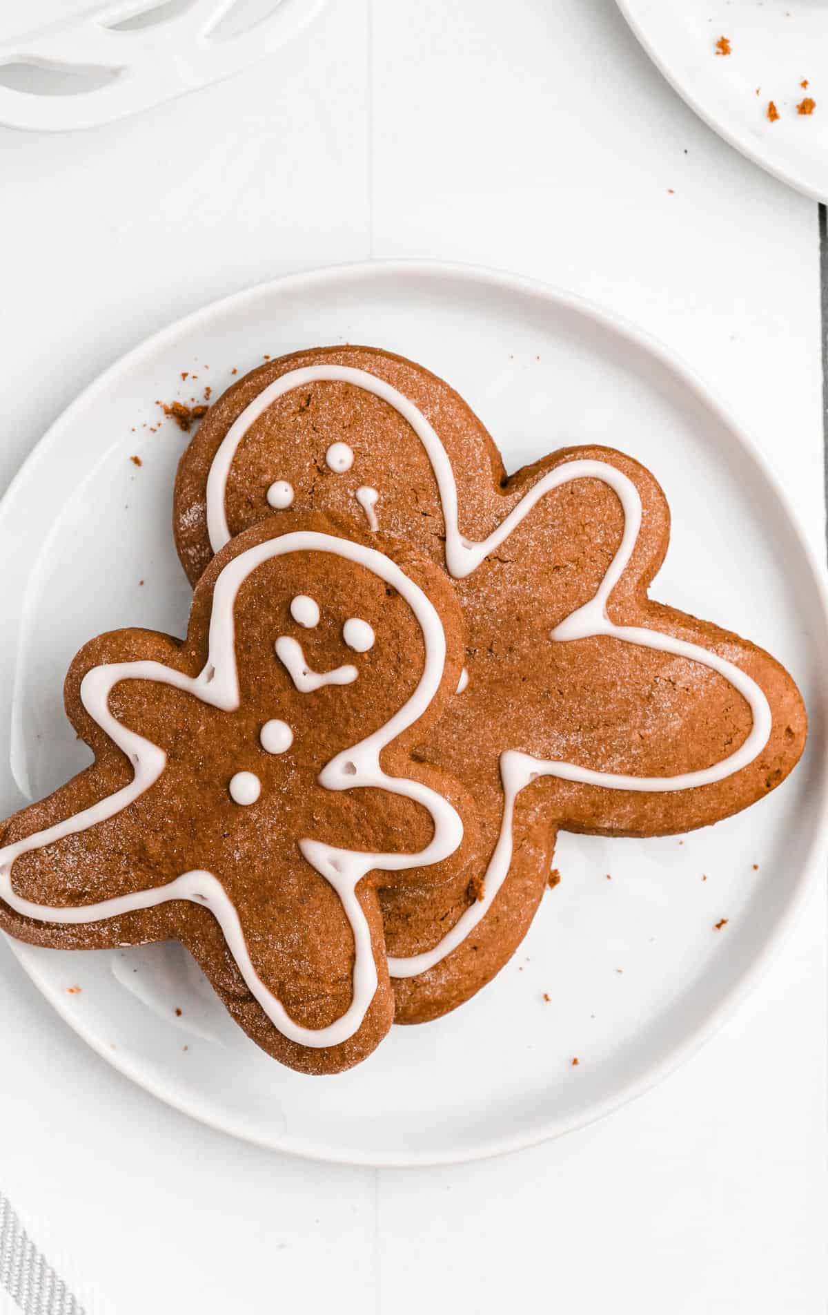 A close up photo of two gingerbread cookies on a white plate.