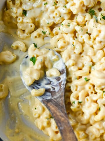 Stovetop macaroni and cheese with a wooden spoon.