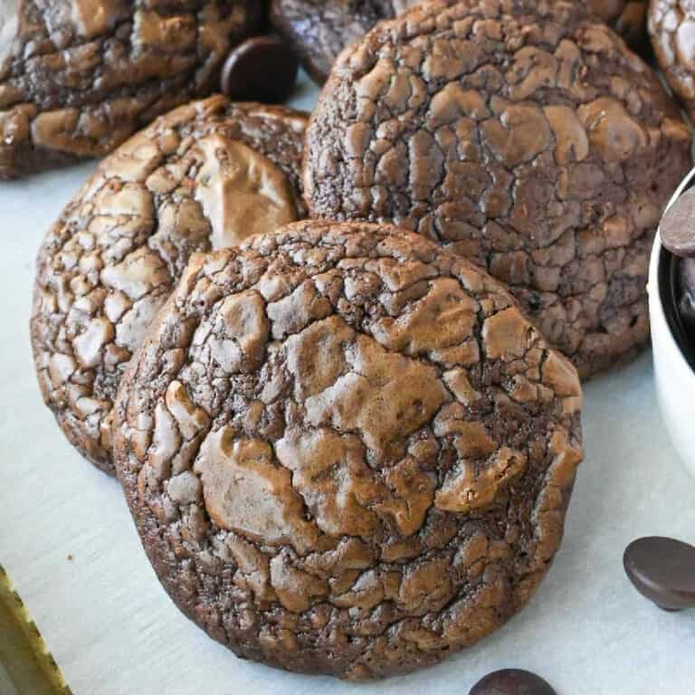Brownie cookies on a baking sheet with some chocolate chips.