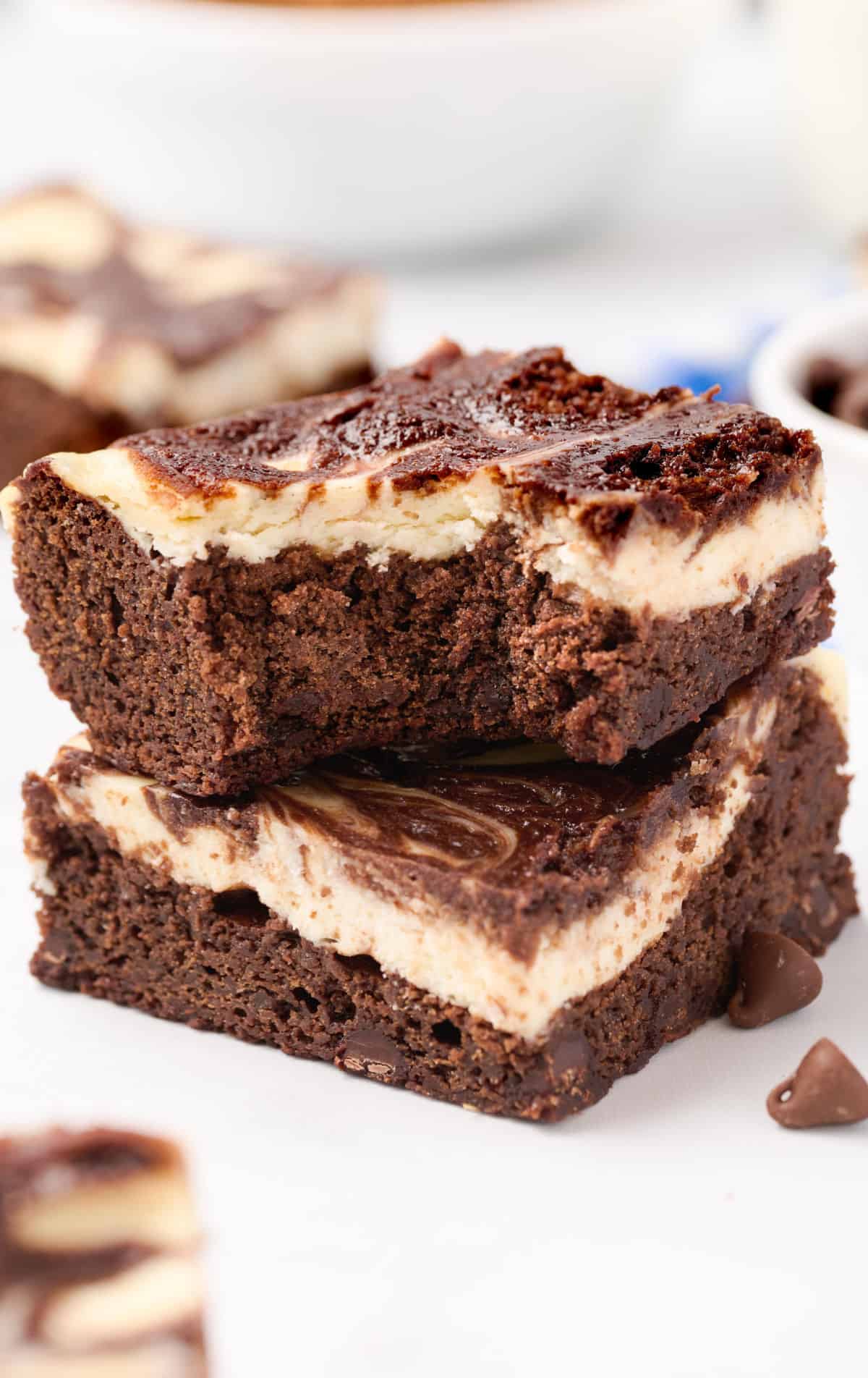 Two brownies stacked and one with a bite out of it.