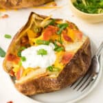 A baked potato loaded with butter, cheese, sour cream and bacon.