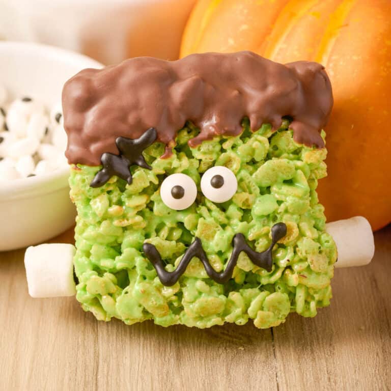 A frankenstein rice krispie treat leaning against a pumpkin.