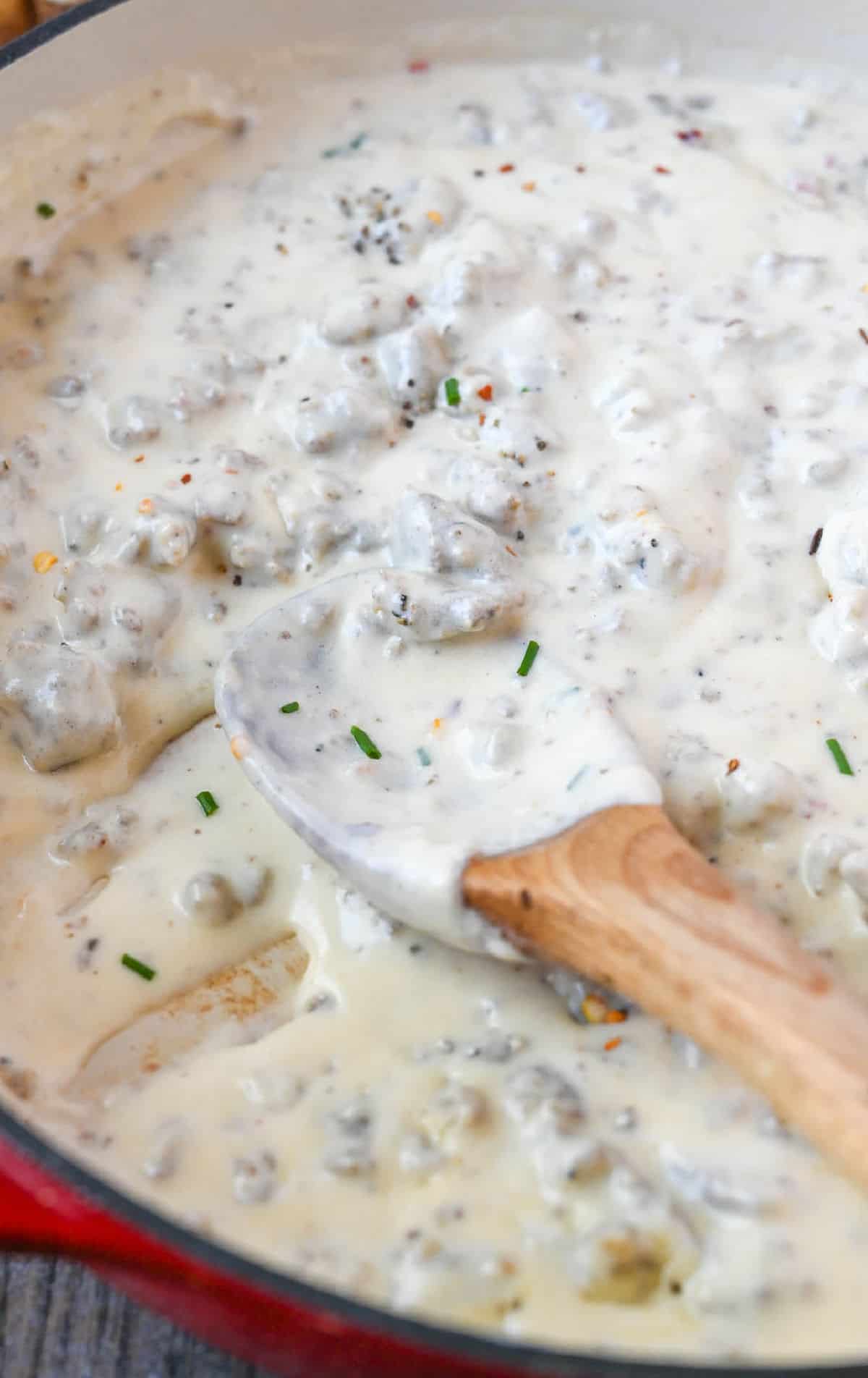 Sausage gravy in a skillet with a wooden spoon.