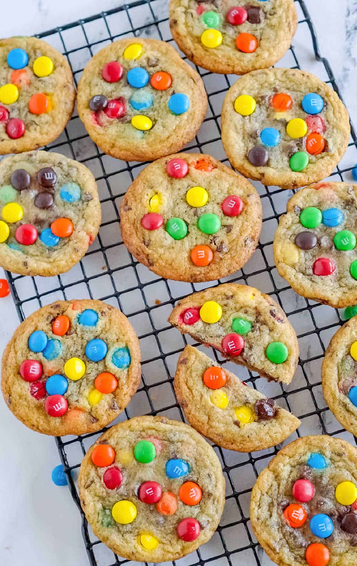 M&M cookies on a cooling rack with one cut in half.