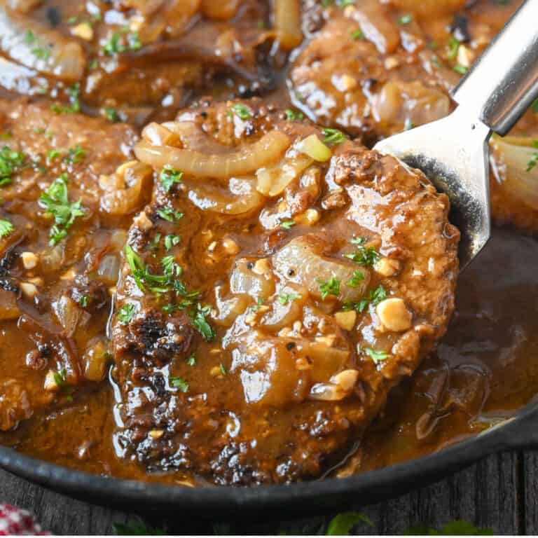 Cube steak with onion gravy being picked up with a spatula.
